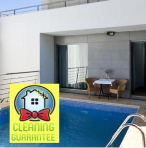 un cartello di fronte a una piscina con una casa con un papillon di Pé na Areia - Guest House a Vila Real de Santo António