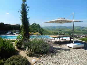 een terras met een tafel en een parasol naast een zwembad bij B&B Bionzo16 in Calosso