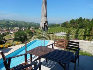 un patio con mesa, sombrilla y piscina en B&B Bionzo16 en Calosso
