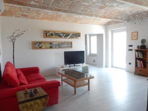 a living room with a red couch and a tv at B&B Bionzo16 in Calosso