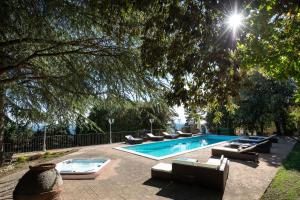 una piscina con tumbonas y un árbol en Villa Piscina “La Trinità “, en Corciano