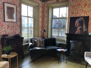 een woonkamer met een bank en een portret van een vrouw bij B&B In het Voorhuys in Zuidlaren