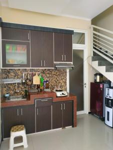 una cocina con armarios de color marrón oscuro y una escalera en Villa Gumilang, en Batu