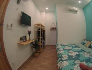 1 dormitorio con 1 cama y TV en la pared en HD House Homestay Vũng Tàu, en Vung Tau