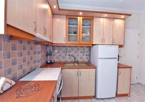 uma cozinha com armários de madeira e um frigorífico branco em Four sons em Flogita