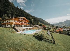 ein Haus auf einem Hügel mit Pool in der Unterkunft Hotel Silberfux in Sankt Veit im Pongau