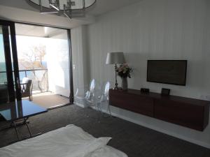 ein Wohnzimmer mit einem Bett, einem TV und einem Balkon in der Unterkunft Apartament 514 Seaside z widokiem na morze in Kołobrzeg