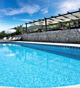 a large blue swimming pool with a stone wall at Tenuta Tropeano in Tropea