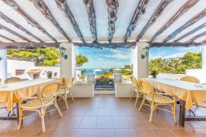 a dining room with tables and chairs and a view of the ocean at Hostal Cala Moli in Cala Tarida