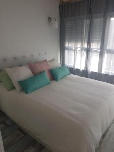 białe łóżko z poduszkami w pokoju w obiekcie APT 6 - Apartamento en la playa de El Palo w Maladze