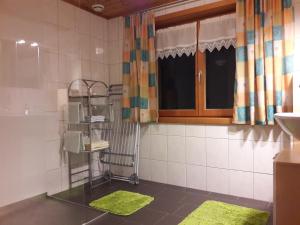 baño con alfombras verdes en el suelo y ventana en Apart Greber en Andelsbuch