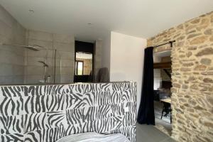 a living room with a zebra print couch and a stone wall at Charmante maison face à l’église de CODOLET in Codolet