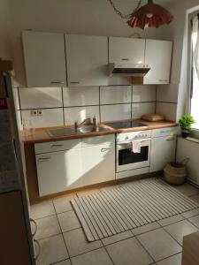 a kitchen with white cabinets and a sink and a stove at Gemütliche 2 Zimmer (citynahe wohnung) in Hildesheim