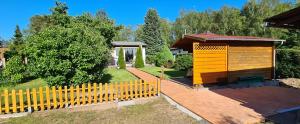 een geel hek in een tuin met een tuinhuisje bij Ferienhaus am Birkenwaeldchen - Motzener See 150m in Mittenwalde