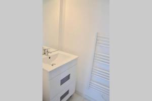 W białej łazience znajduje się umywalka i lustro. w obiekcie La petite maison appartement 2 w mieście Avoine