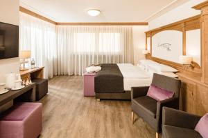 una camera d'albergo con letto e sedia di Giardin Boutique Hotel B&B a Selva di Val Gardena