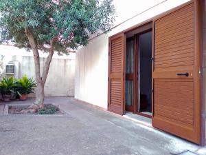 a house with a wooden door and a tree at Casa Liliana in Oristano