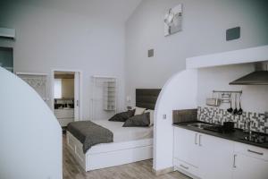 a white bedroom with a bed and a kitchen at ERES EMÉRITA "Apartamentos & Suites" in Mérida
