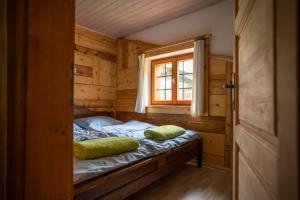 a bed in a wooden room with a window at Holiday Home Srednja vas in Srednja Vas v Bohinju