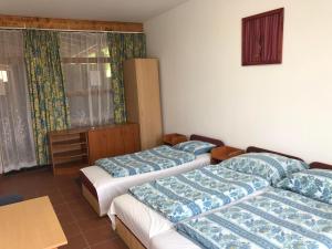 a room with three beds and a table and a window at Beach Hostel Balatonboglár in Balatonboglár