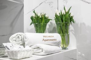 a bathroom shelf with towels and vases with flowers at PREMIUM Apartments New Town Private Parking Included in Szczecin +37 photos