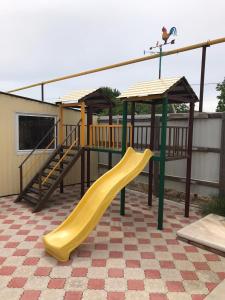 a playground with a yellow slide and a play structure at Гостевой дом Арарат in Dolzhanskaya