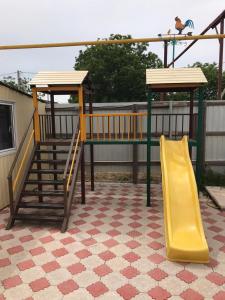 a playground with a yellow slide and a swing at Гостевой дом Арарат in Dolzhanskaya
