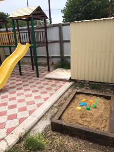 a playground with a sandbox and a slide at Гостевой дом Арарат in Dolzhanskaya