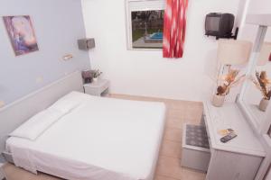 a white bedroom with a bed and a tv at Marika's Apart's & Studios in Pastida