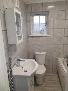 a bathroom with a toilet and a sink and a window at Barnfield Place in Edgware