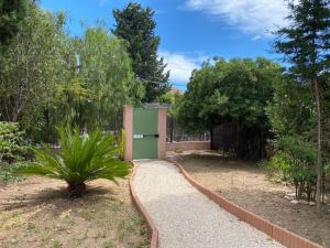 un jardín con una valla y una planta frente a un edificio en Petite maison au calme avec jardin clim et parking en Toulon