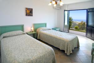 a hotel room with two beds and a balcony at Residence Galati in Capo dʼOrlando