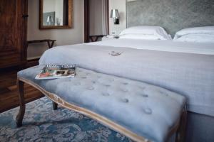a bedroom with a bed and a bench with a magazine on it at Villa Fontana Relais Suite & Spa in Agliano Terme