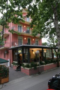 ein rosafarbenes Gebäude mit einem Restaurant davor in der Unterkunft Hotel Villa Rossi in Bellaria-Igea Marina