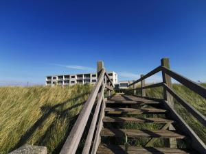 Un escalier en bois mène à un bâtiment sur la plage. dans l'établissement Hotel de Milliano, à Breskens