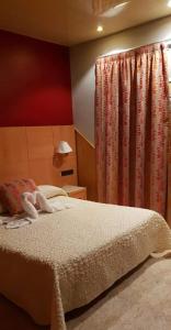1 dormitorio con cama y cortina roja en Hostal Milenium, en Els Monjos