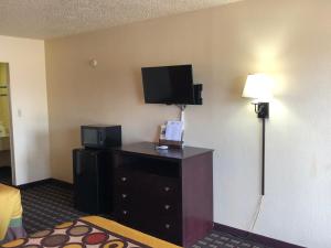 Habitación de hotel con TV y cómoda con lámpara. en Executive Inn & Suites Prescott en Prescott
