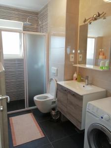 a bathroom with a toilet and a sink and a washing machine at Apartment Mery in Trogir