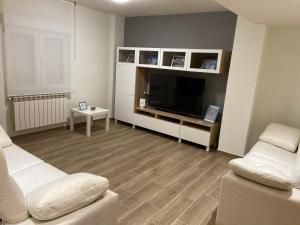 sala de estar con TV de pantalla plana y muebles blancos en piso avenida 49, en Gijón