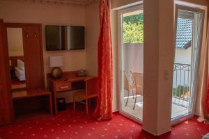 um quarto de hotel com uma secretária e uma porta de vidro deslizante em Hotel-Restaurant Laux em Merzig
