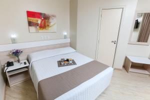 a bedroom with a white bed and white walls at Hotel Express Aeroporto in Porto Alegre