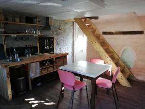 比埃夫勒的住宿－Graide Retreat Lodge，厨房配有桌子和4把粉红色的椅子