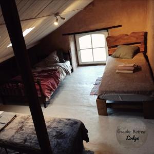 1 dormitorio en el ático con 2 camas y ventana en Graide Retreat Lodge, en Bièvre