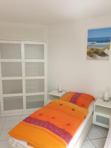 a bedroom with a bed with an orange blanket at Ferienwohnung Sonnenblick mit 3 Zimmer und Balkon in Zempin