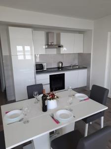 - une cuisine avec une table blanche, des chaises et des verres à vin dans l'établissement Apartmani Antea, à Starigrad-Paklenica