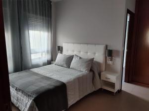 1 dormitorio con 1 cama con cabecero blanco y ventana en Apartamento Playa de Coira II, en Portosín