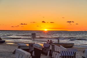 two people standing on the beach watching the sunset at Ferienwohnung Sonnenblick mit 3 Zimmer und Balkon in Zempin