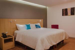a bedroom with a large white bed with blue pillows at Hotel Kavia Monterrey in Monterrey