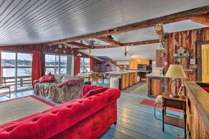 ein Wohnzimmer mit einem roten Sofa und einer Küche in der Unterkunft Quiet Cabin on Glen Lake with Boat Dock and Deck! in Queensbury