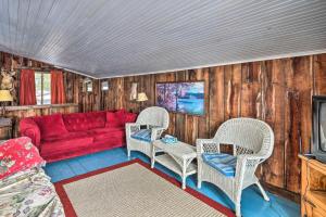 uma sala de estar com um sofá vermelho e duas cadeiras em Quiet Cabin on Glen Lake with Boat Dock and Deck! em Queensbury